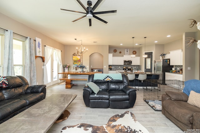 living room featuring light wood-type flooring and ceiling fan with notable chandelier