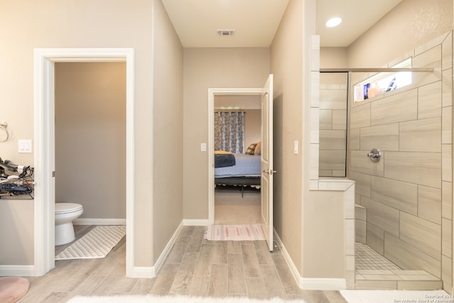 bathroom with a tile shower, hardwood / wood-style flooring, and toilet