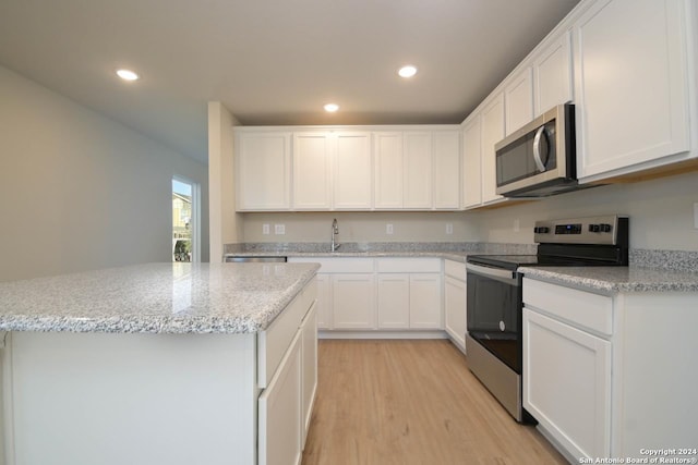 kitchen featuring white cabinetry, stainless steel appliances, light stone counters, and light hardwood / wood-style floors