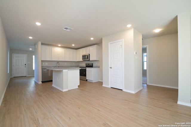 kitchen featuring white cabinets, a kitchen island, light wood-type flooring, and appliances with stainless steel finishes