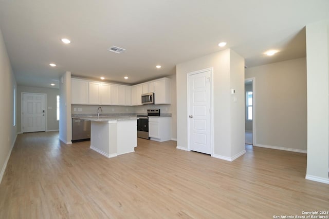 kitchen with white cabinets, a center island, light wood-type flooring, and appliances with stainless steel finishes