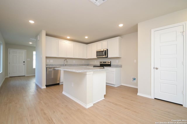 kitchen featuring white cabinets, light hardwood / wood-style floors, a kitchen island, and appliances with stainless steel finishes