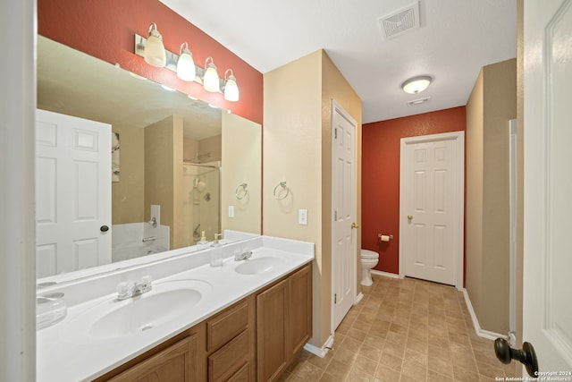 bathroom with tile floors, dual sinks, oversized vanity, and toilet