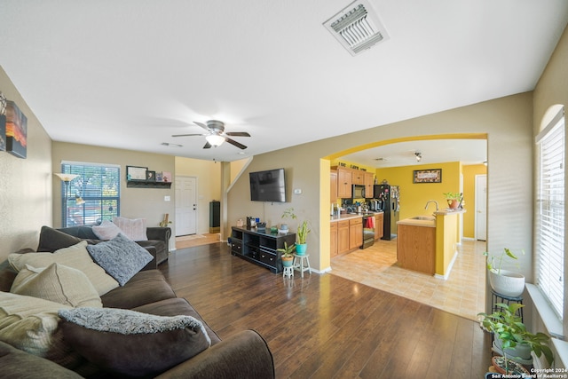 living room with sink, light wood-type flooring, and ceiling fan