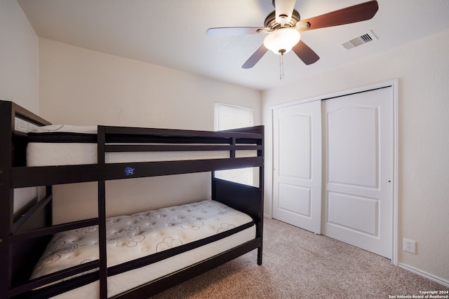 carpeted bedroom with ceiling fan and a closet