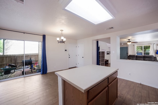 kitchen featuring ceiling fan with notable chandelier, a textured ceiling, dark wood-type flooring, pendant lighting, and a center island