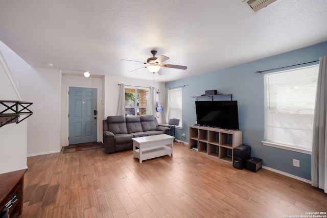 living room with a textured ceiling, light hardwood / wood-style flooring, and ceiling fan