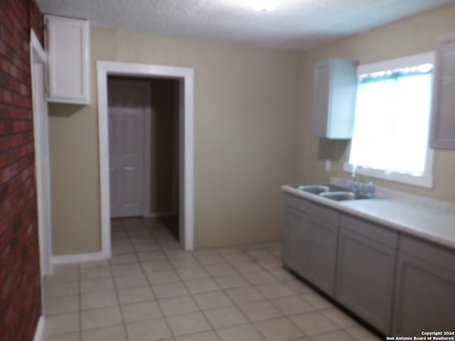 kitchen featuring white cabinets, light tile patterned floors, and sink