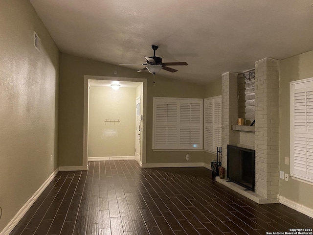 unfurnished living room featuring ceiling fan, dark hardwood / wood-style flooring, lofted ceiling, and a brick fireplace