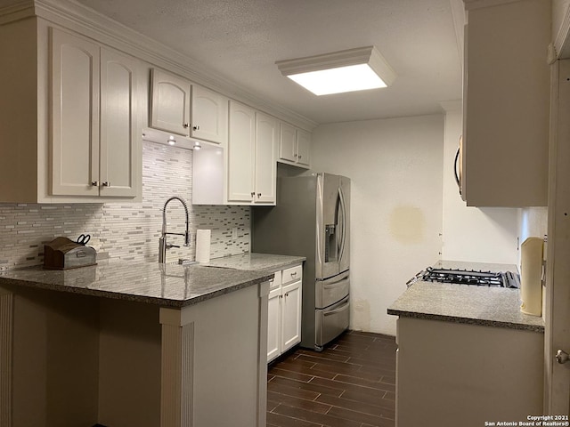 kitchen featuring stone counters, white cabinets, kitchen peninsula, tasteful backsplash, and stainless steel fridge with ice dispenser