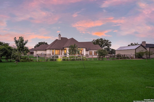 back house at dusk with a lawn