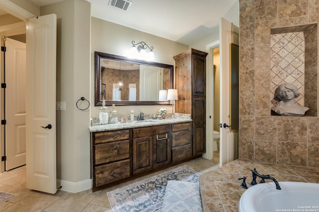 bathroom featuring tile patterned floors, vanity, toilet, and a bathing tub