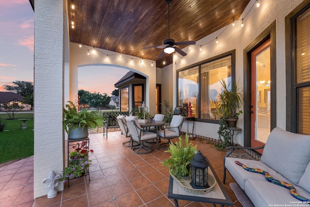 patio terrace at dusk with ceiling fan and an outdoor living space