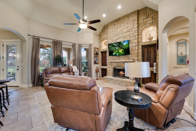 tiled living room with high vaulted ceiling, a stone fireplace, and ceiling fan