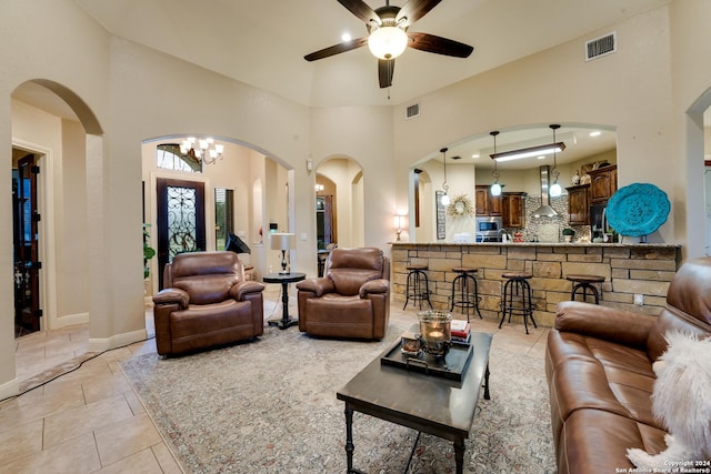 tiled living room with ceiling fan with notable chandelier