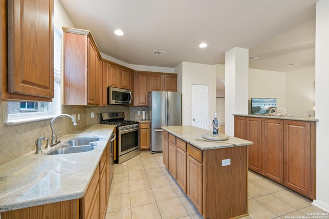 kitchen featuring sink, light tile patterned floors, stainless steel appliances, a center island, and light stone countertops