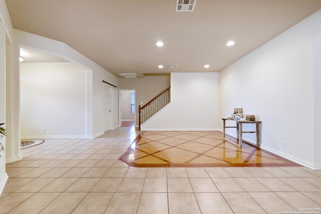 empty room featuring a barn door and light tile patterned flooring