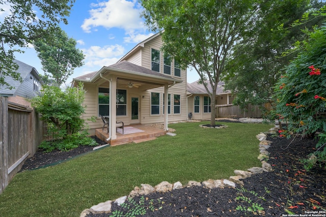 rear view of house with ceiling fan and a lawn