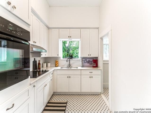 kitchen featuring black appliances, white cabinets, sink, and exhaust hood