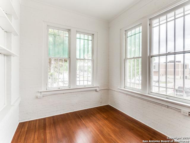 unfurnished room featuring a wealth of natural light, ornamental molding, and hardwood / wood-style flooring