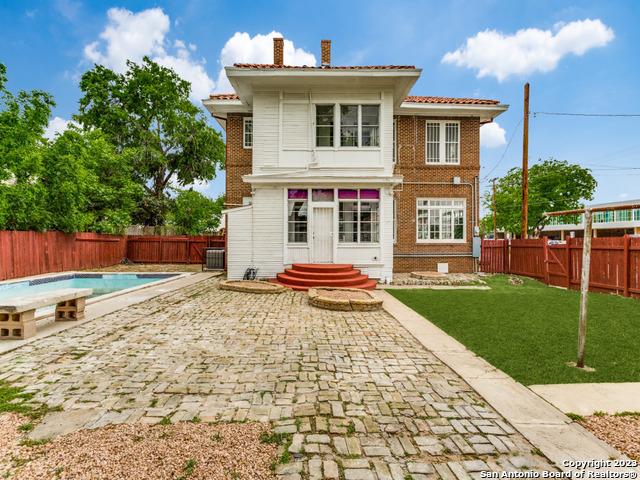 rear view of house featuring a yard, a patio, a fenced in pool, and central air condition unit