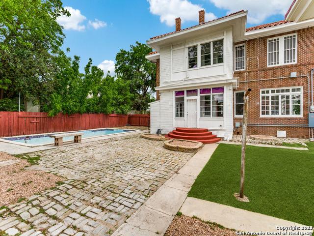 back of house featuring a patio, a fenced in pool, and a lawn