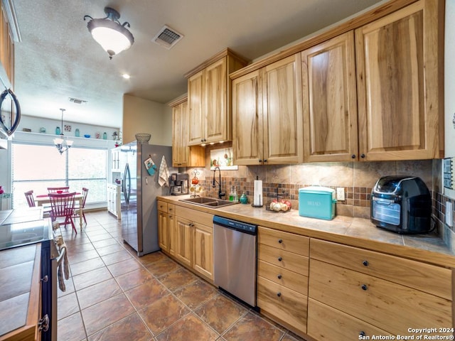 kitchen featuring a sink, visible vents, appliances with stainless steel finishes, tile counters, and tasteful backsplash