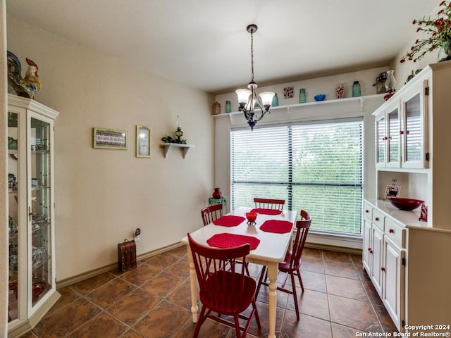 dining area featuring a chandelier, dark tile patterned floors, and baseboards