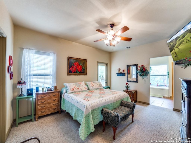 bedroom featuring light colored carpet, ceiling fan, baseboards, and light tile patterned flooring