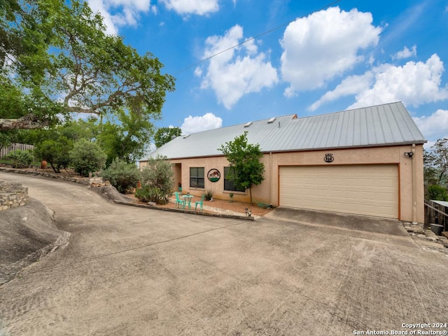 view of front of property featuring concrete driveway, metal roof, an attached garage, and stucco siding