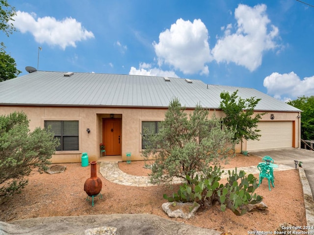 view of front of house featuring stucco siding, a standing seam roof, metal roof, a garage, and driveway