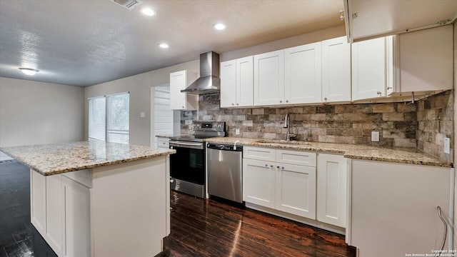 kitchen featuring sink, wall chimney exhaust hood, tasteful backsplash, white cabinets, and appliances with stainless steel finishes