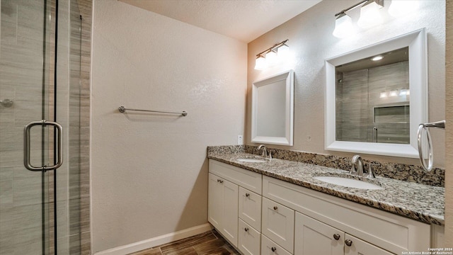 bathroom with vanity, a shower with shower door, and a textured ceiling