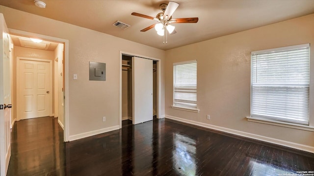 unfurnished bedroom featuring ceiling fan, dark hardwood / wood-style floors, electric panel, multiple windows, and a closet