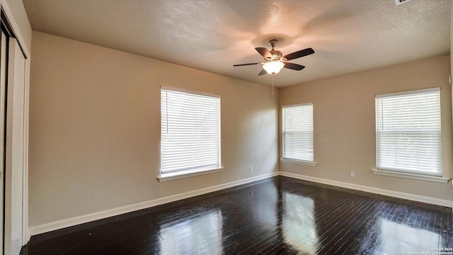 unfurnished room featuring plenty of natural light, dark hardwood / wood-style flooring, and a textured ceiling