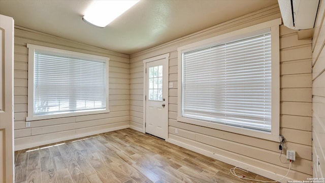 foyer with wood walls, lofted ceiling, and light wood-type flooring