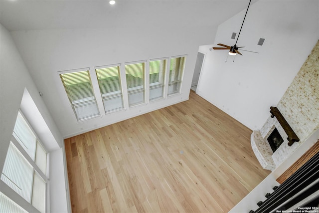 unfurnished living room featuring a fireplace, hardwood / wood-style flooring, high vaulted ceiling, and ceiling fan