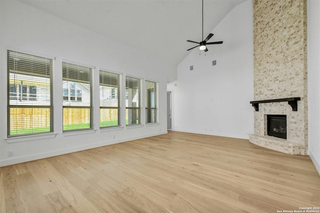 unfurnished living room featuring a fireplace, light hardwood / wood-style flooring, high vaulted ceiling, and ceiling fan