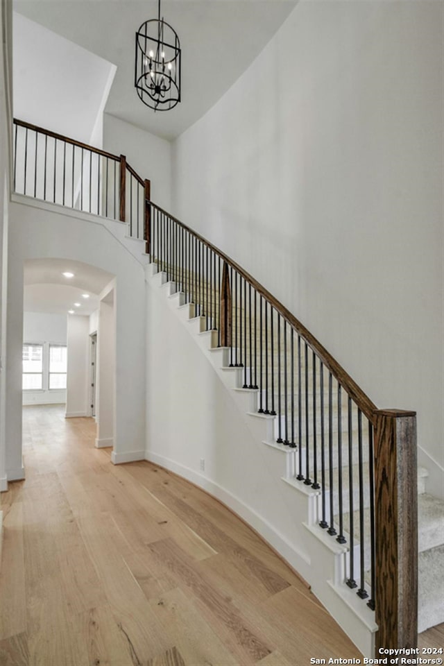 stairs featuring hardwood / wood-style flooring, a high ceiling, and a chandelier