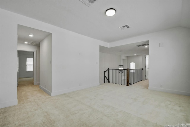 carpeted spare room featuring an inviting chandelier