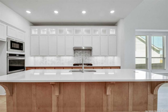 kitchen with white cabinets, decorative backsplash, a spacious island, and stainless steel appliances