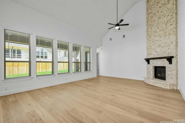 unfurnished living room featuring ceiling fan, a fireplace, high vaulted ceiling, and light wood-type flooring