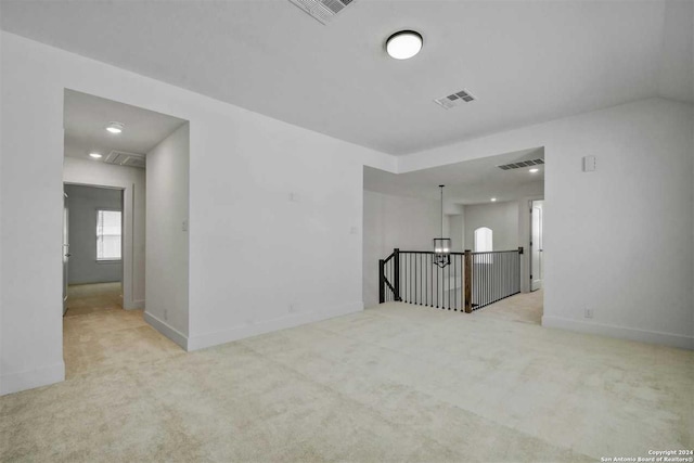 empty room featuring light carpet and a chandelier