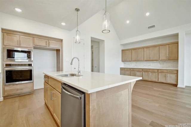 kitchen featuring appliances with stainless steel finishes, sink, a center island with sink, light hardwood / wood-style flooring, and decorative light fixtures