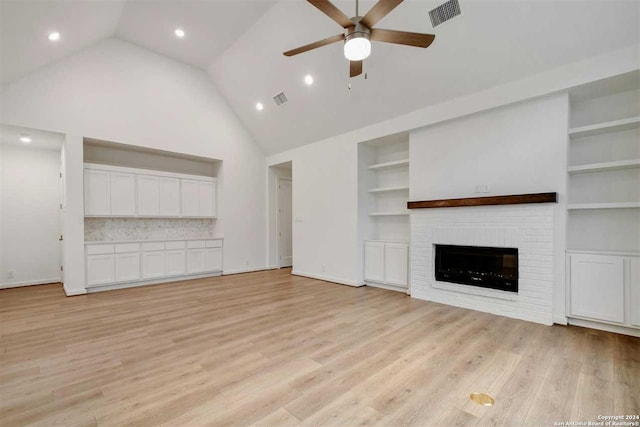 unfurnished living room with built in shelves, ceiling fan, high vaulted ceiling, a fireplace, and light hardwood / wood-style floors