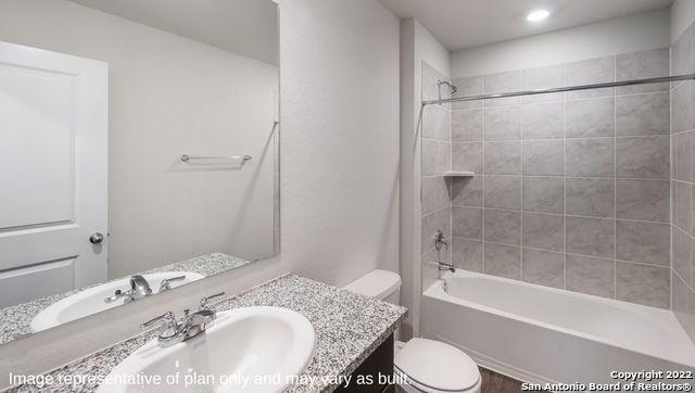 full bathroom with tiled shower / bath combo, vanity, and toilet