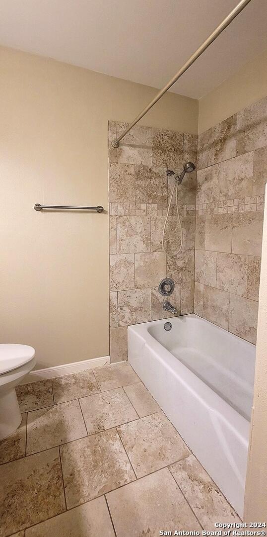 bathroom featuring toilet and tiled shower / bath