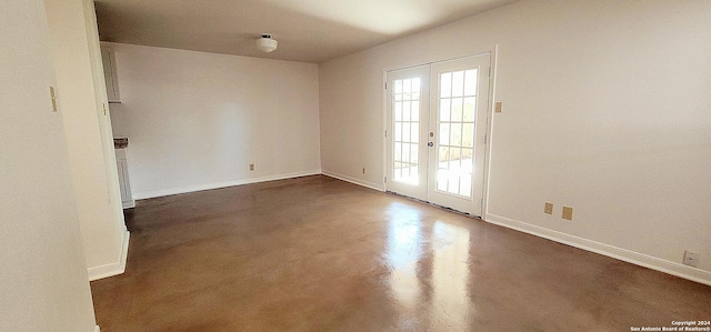 unfurnished room with french doors, concrete flooring, and baseboards