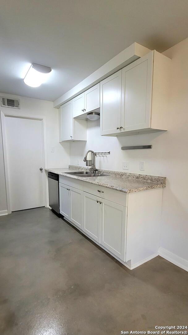 kitchen with stainless steel dishwasher, white cabinetry, and sink