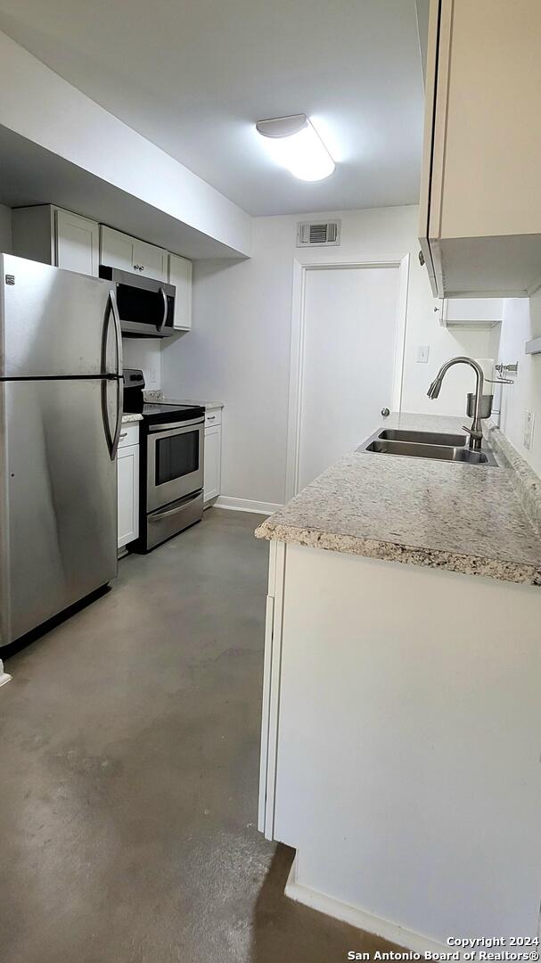 kitchen with sink, concrete floors, and appliances with stainless steel finishes